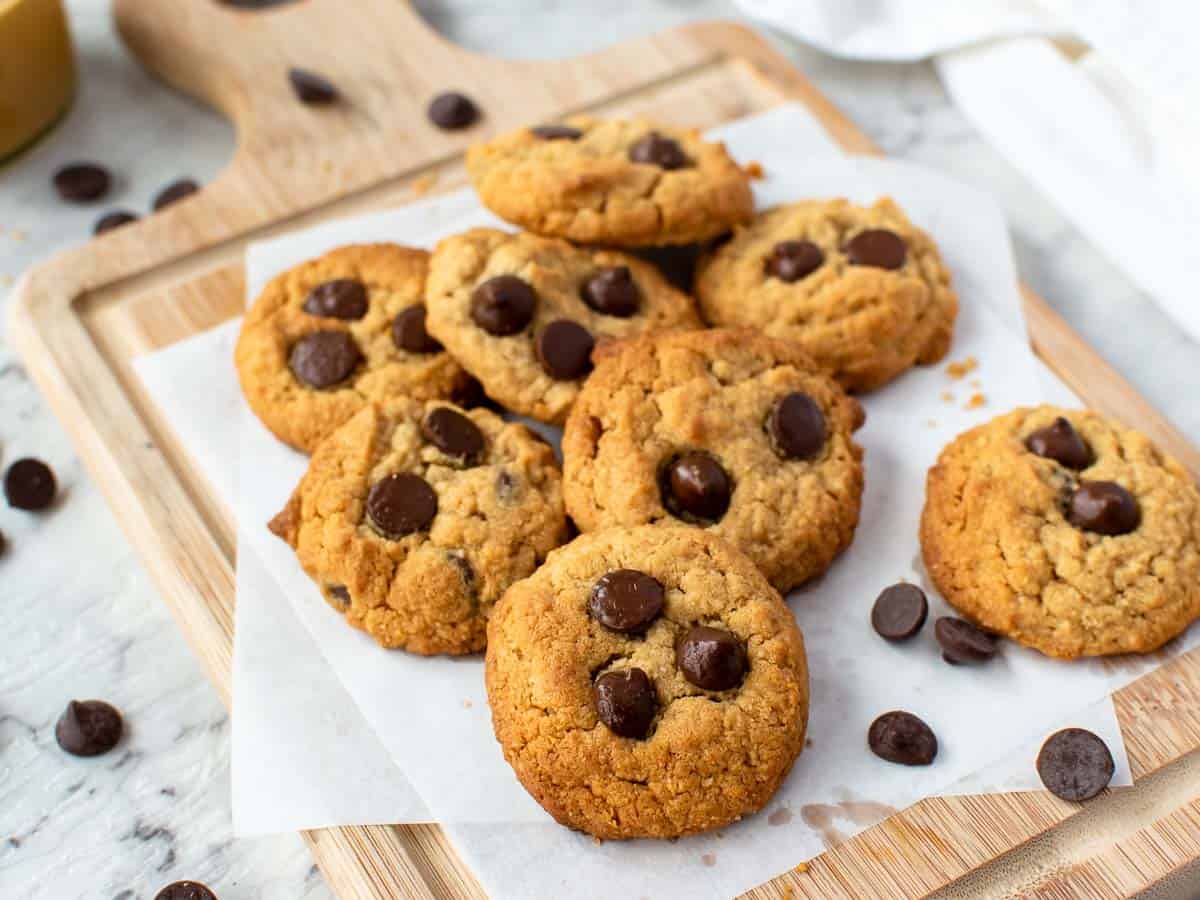 Cookies topped with chocolate chips on a wooden board.