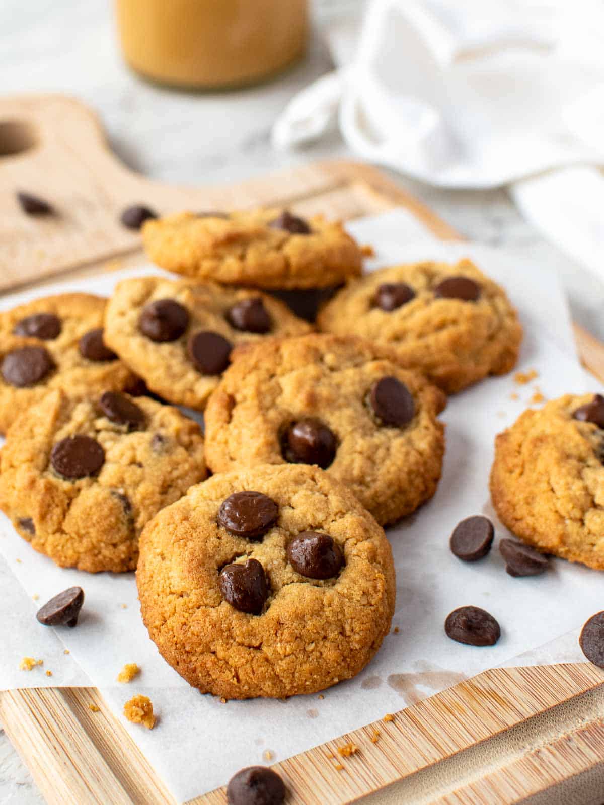 Almond flour peanut butter cookies topped with chocolate chips on white baking sheet.