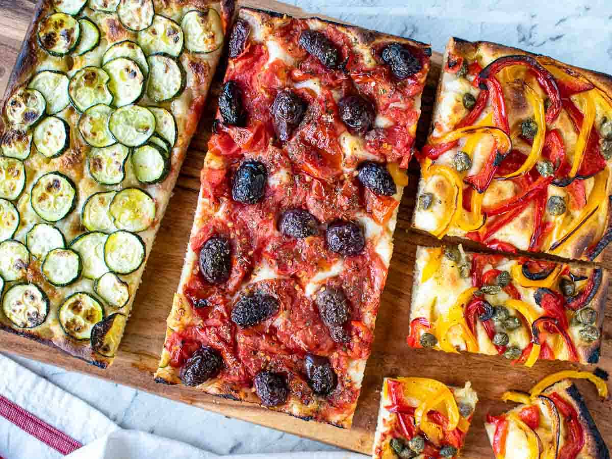 Rectangle focaccia topped with three different toppings viewed from above.