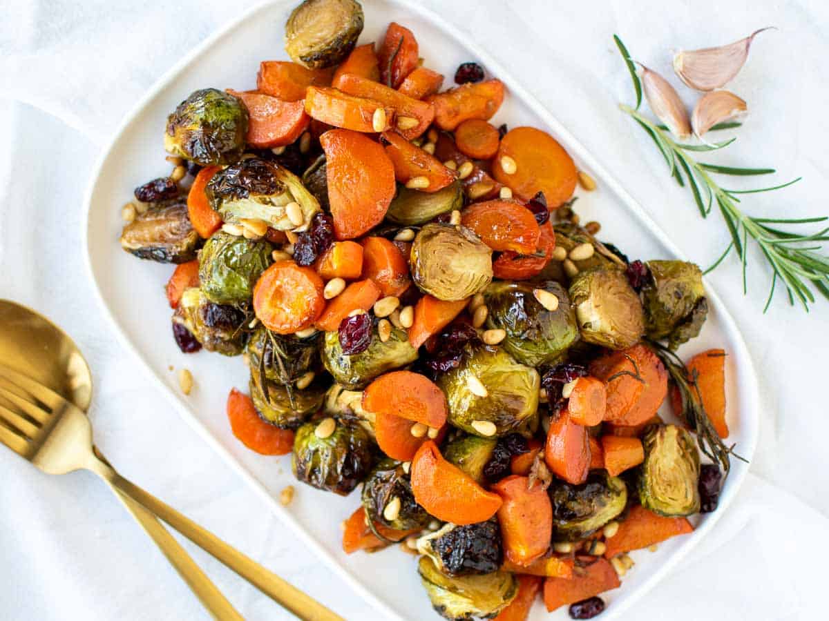 roasted carrots and brussels sprouts on white oblong plate viewed from above.