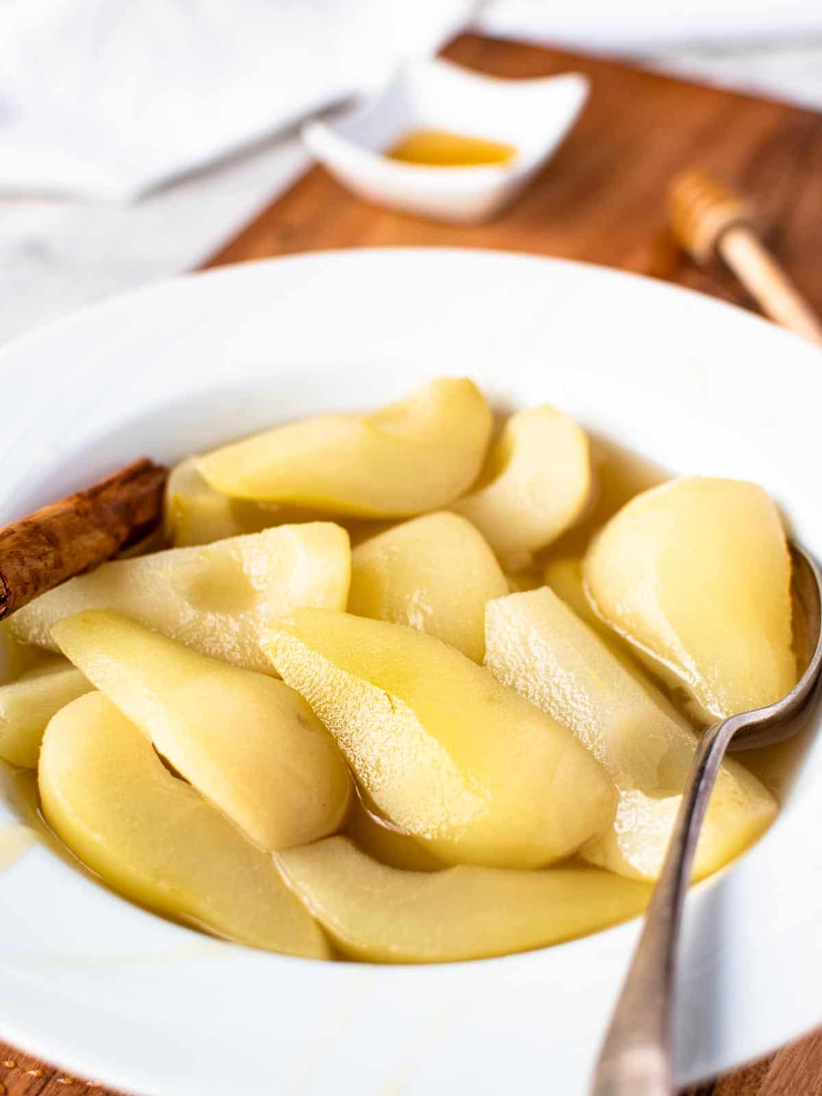 stewed pears in a white large rimmed bowl with spoon.