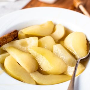 stewed pears in a white large rimmed bowl with spoon.