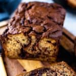 image with text. text reads 'banana bread with nutella". image is Several slices of baked banana bread with swirls of nutella running through them on a wooden board.