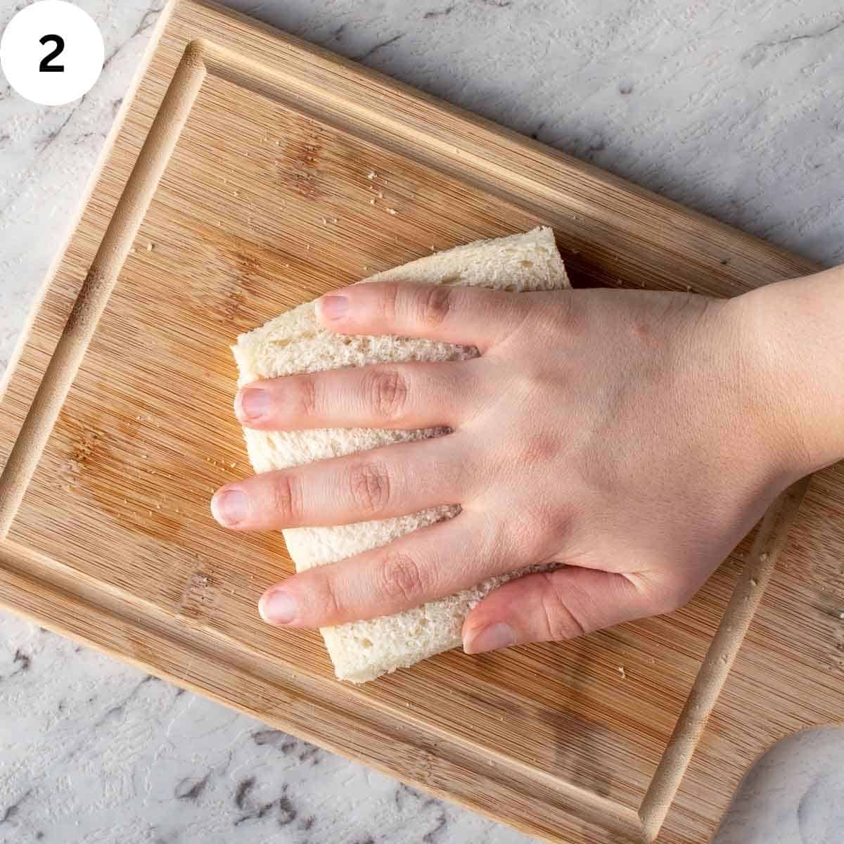 Pressing on  a white bread sandwhich with hand.