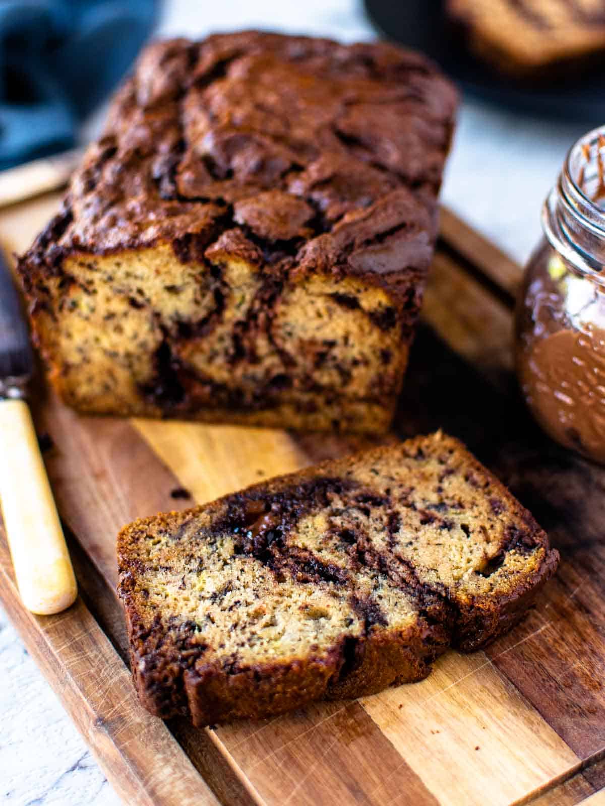 Several slices of baked banana bread with swirls of nutella running through them on a wooden board.