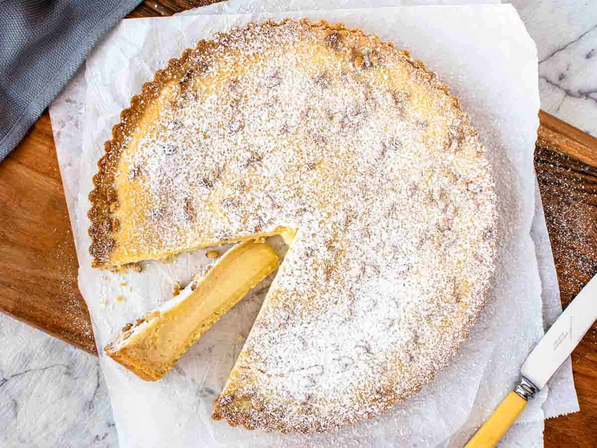 Pie with pastry cream filling dusted with powdered sugar with a slice cut and turned so that the filling is revealed viewed from above.