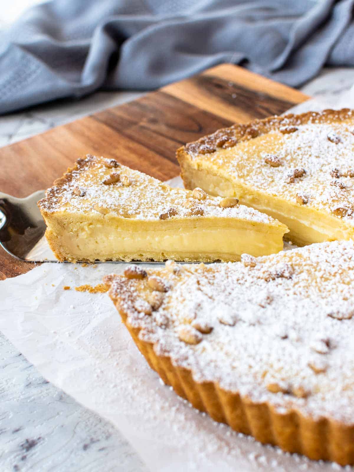 Torta della Nonna with pastry cream filling with a slice cut and pulled out.