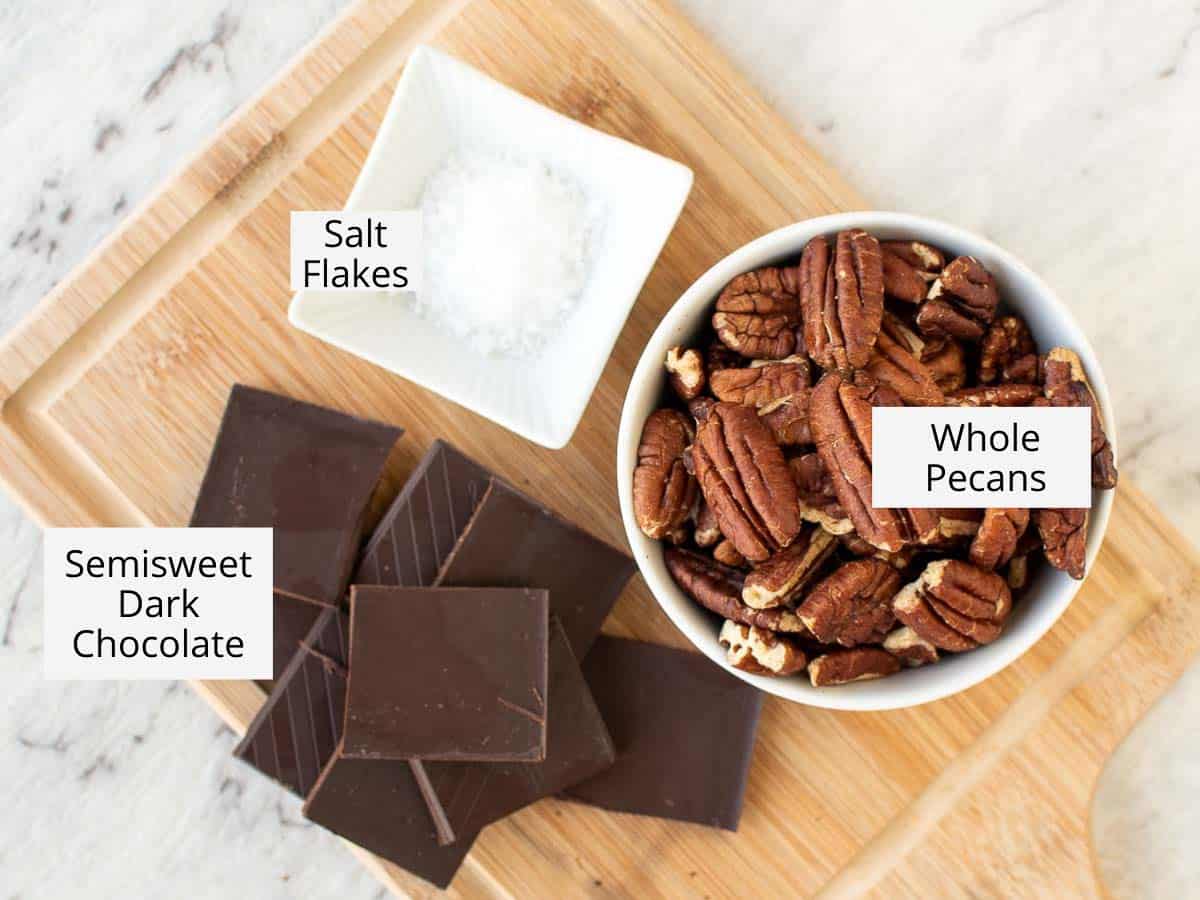 pecans, chocolate and salt on wooden board viewed from above.