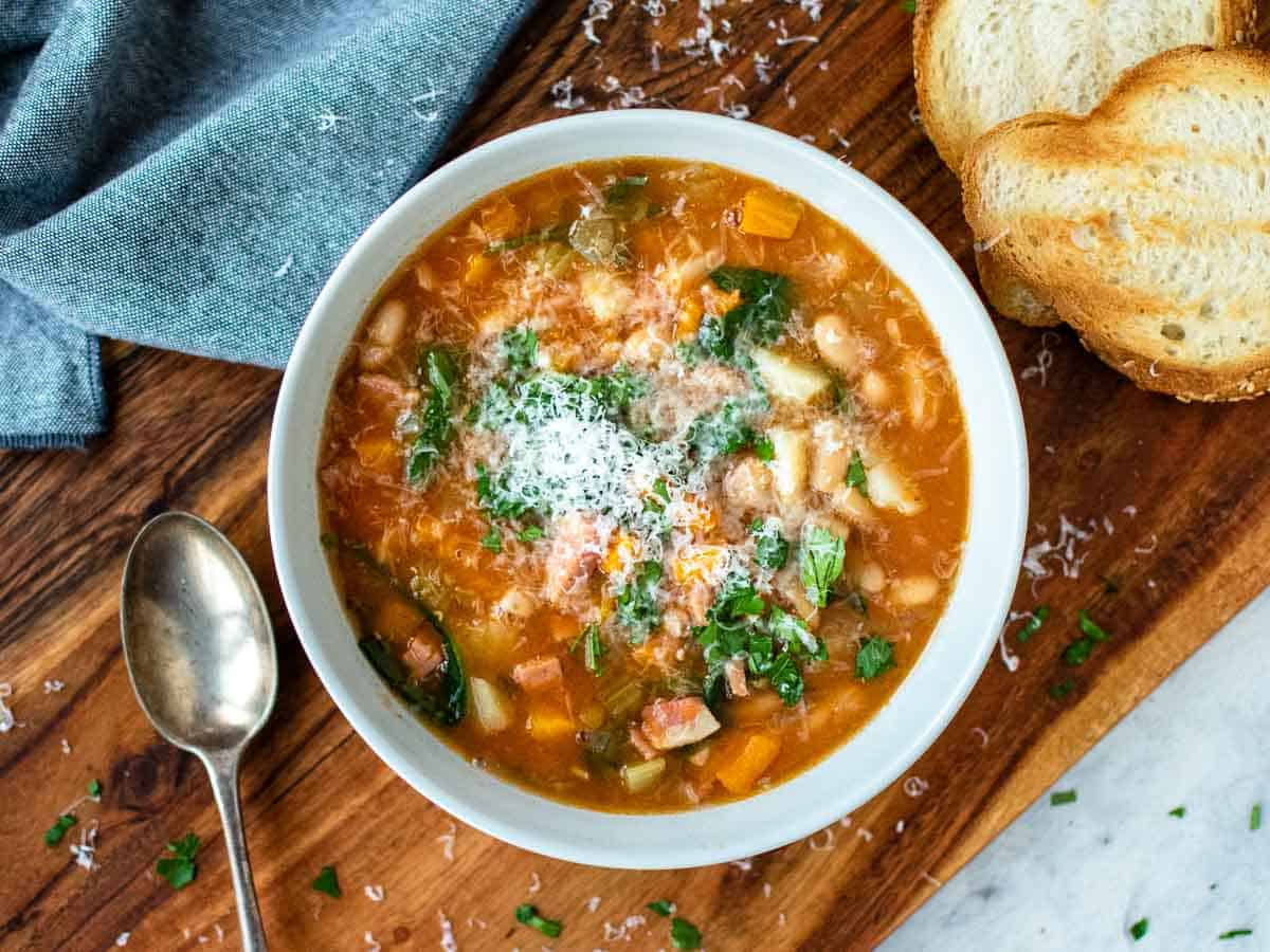 thick bean soup in a pale blue bowl on wooden board seen from above.