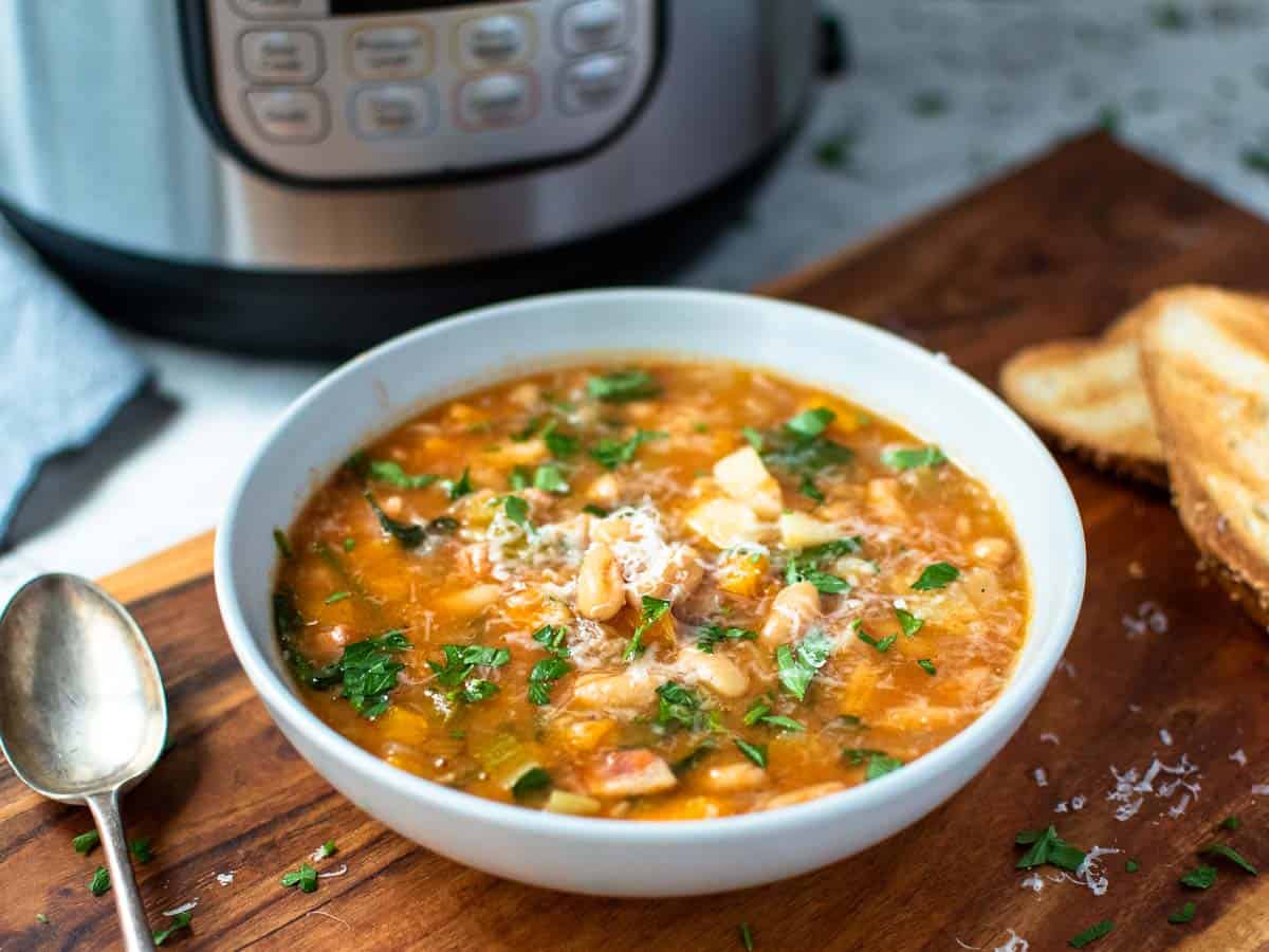 thick bean soup in pale blue bowl with instant pot in the background.