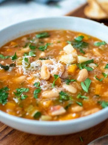 instant pot cannellini bean soup in a pale blue bowl on wooden board.