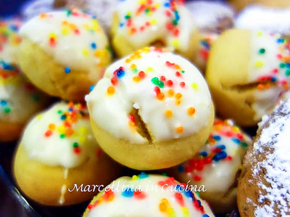 close up of round cookies with white icing and colored nonpareils.