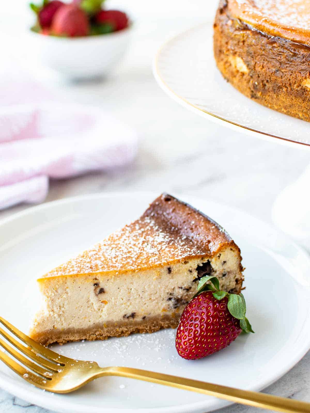 A slice of Sicilian cheesecake on a white plate with a strawberry on the side.