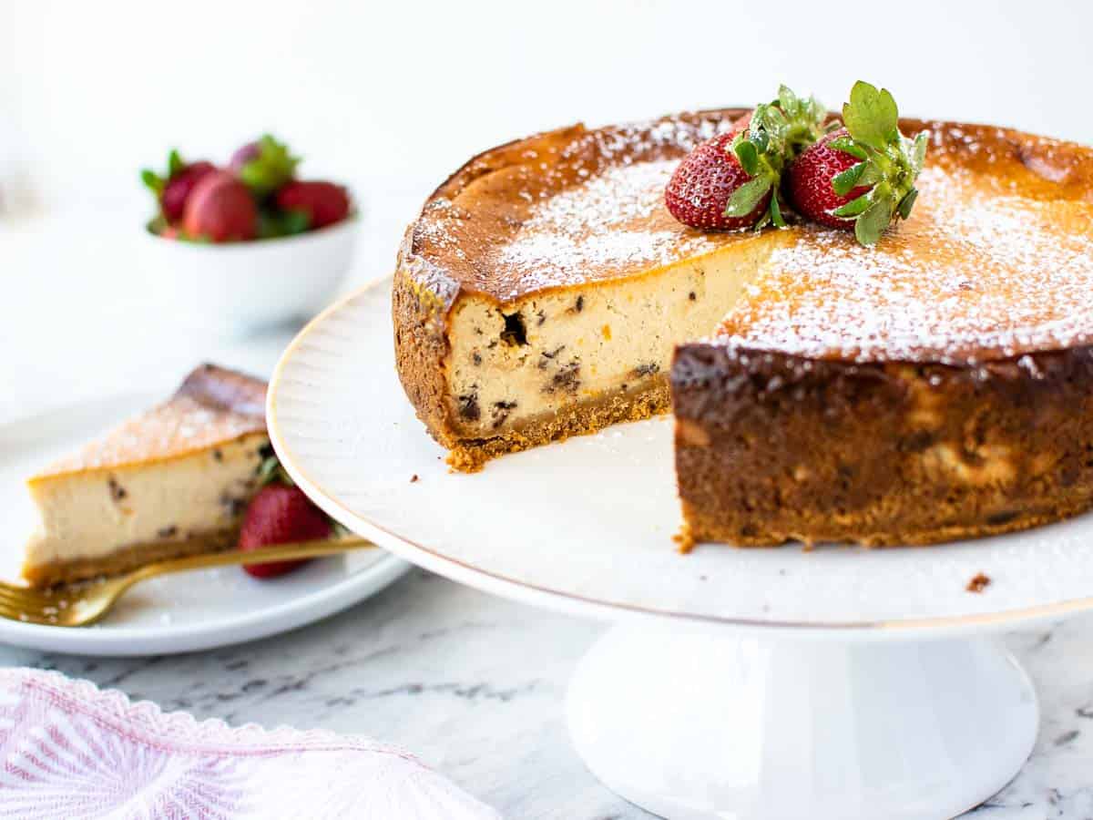 golden brown, round dessert with 3 strawberries on top and a slice removed.