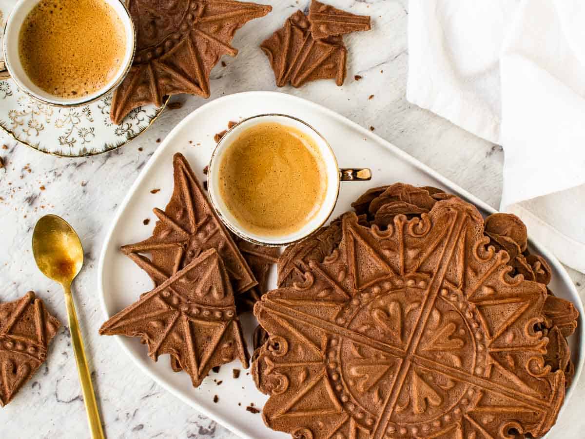 chocolate wafer cookies on white plate with two espresso coffees in cup.