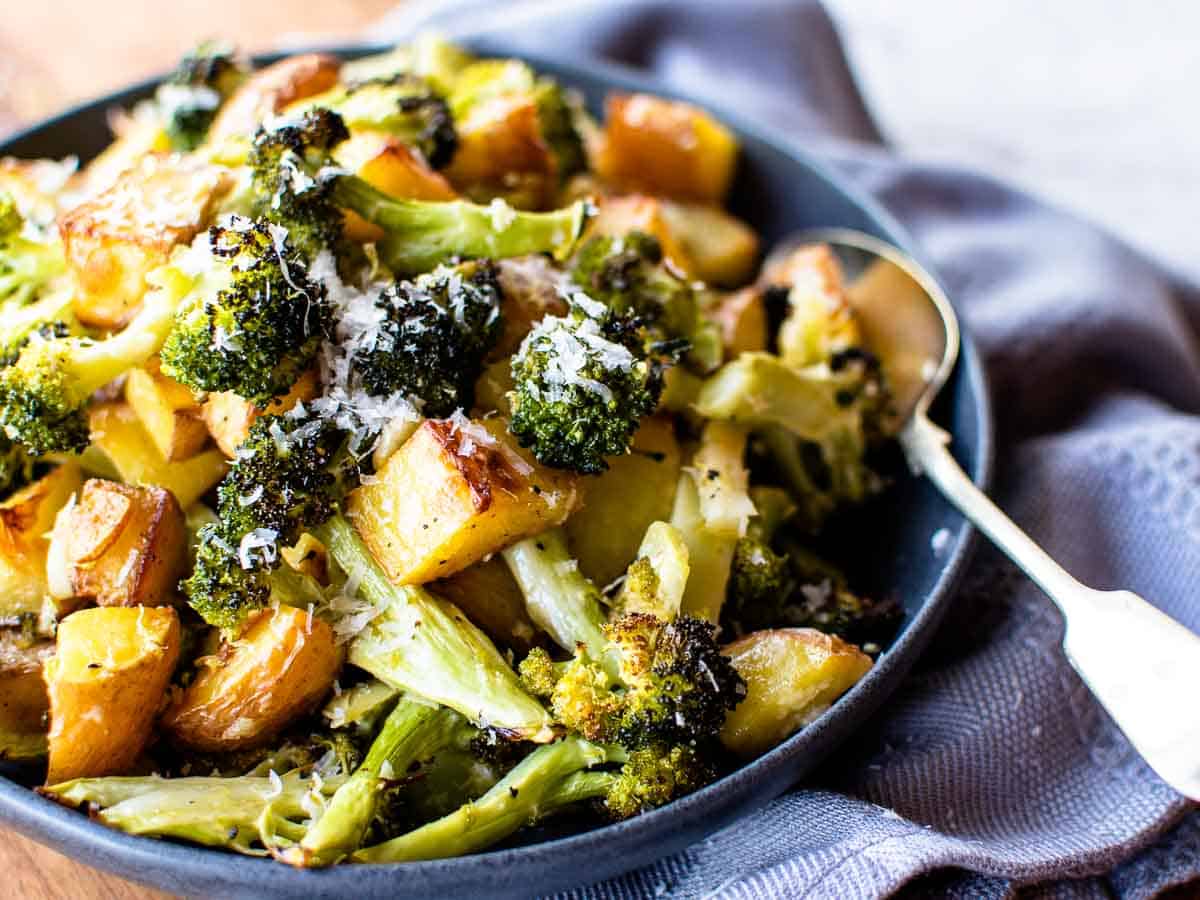 close up of the roasted vegetable side dish in a bowl with a spoon.