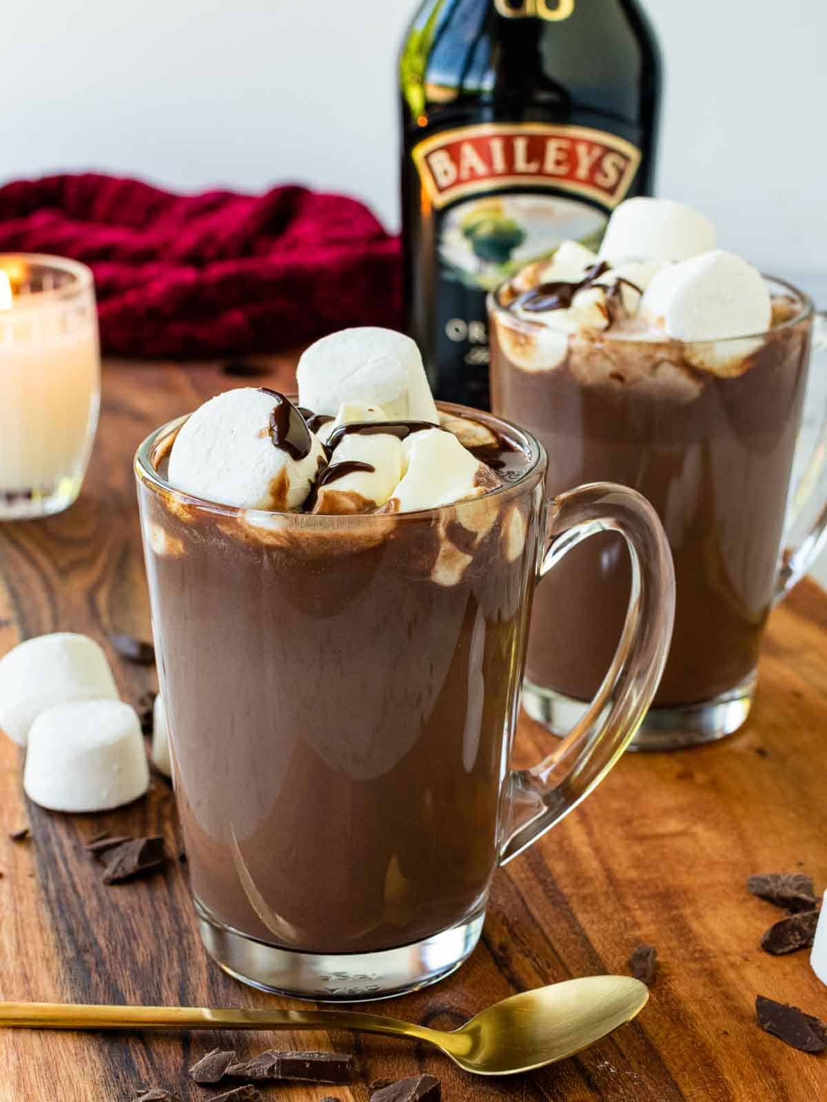 Two mugs of Baileys hot chocolate with bottle of baileys irish cream in the background.