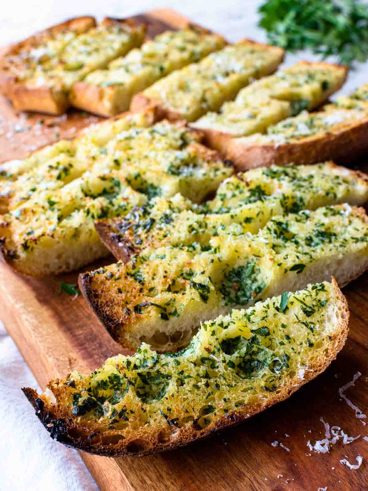 Slices of toasted ciabatta garlic bread topped with herbs.