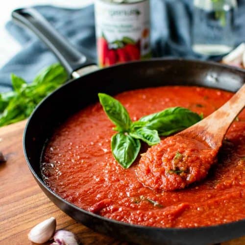 tomato sauce in a black skillet with a sprig of basil in the centre.