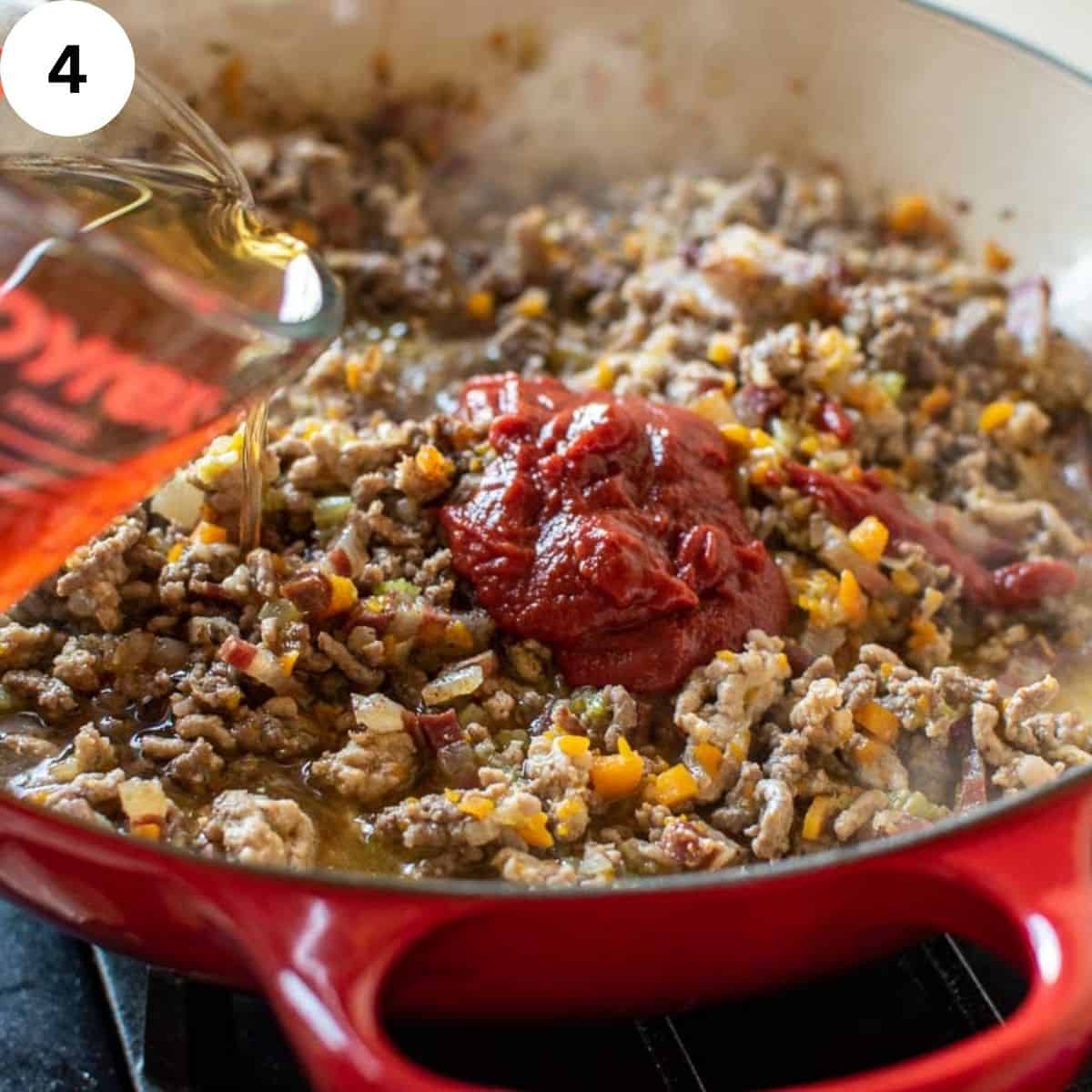Beef stock being added to browned ground meat.