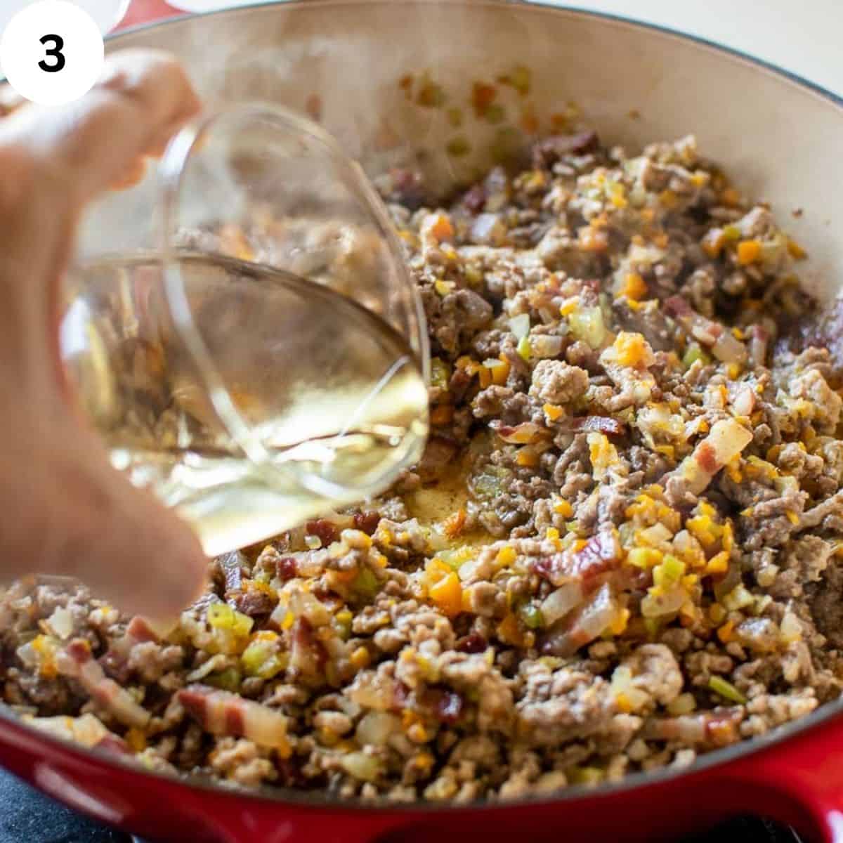White wine being poured into browned ground meat.