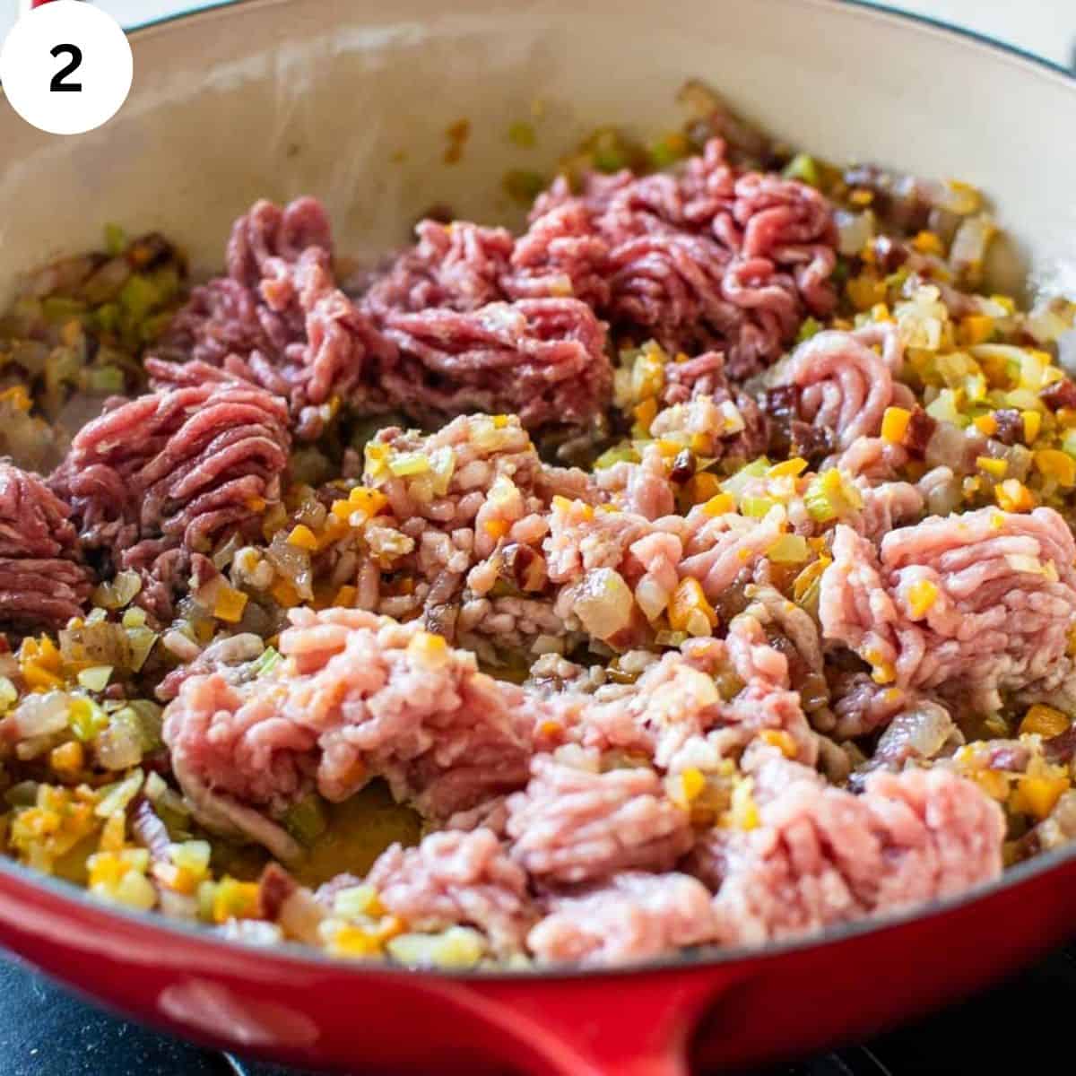 Ground meat being sauteed in a pan with chopped vegetables.