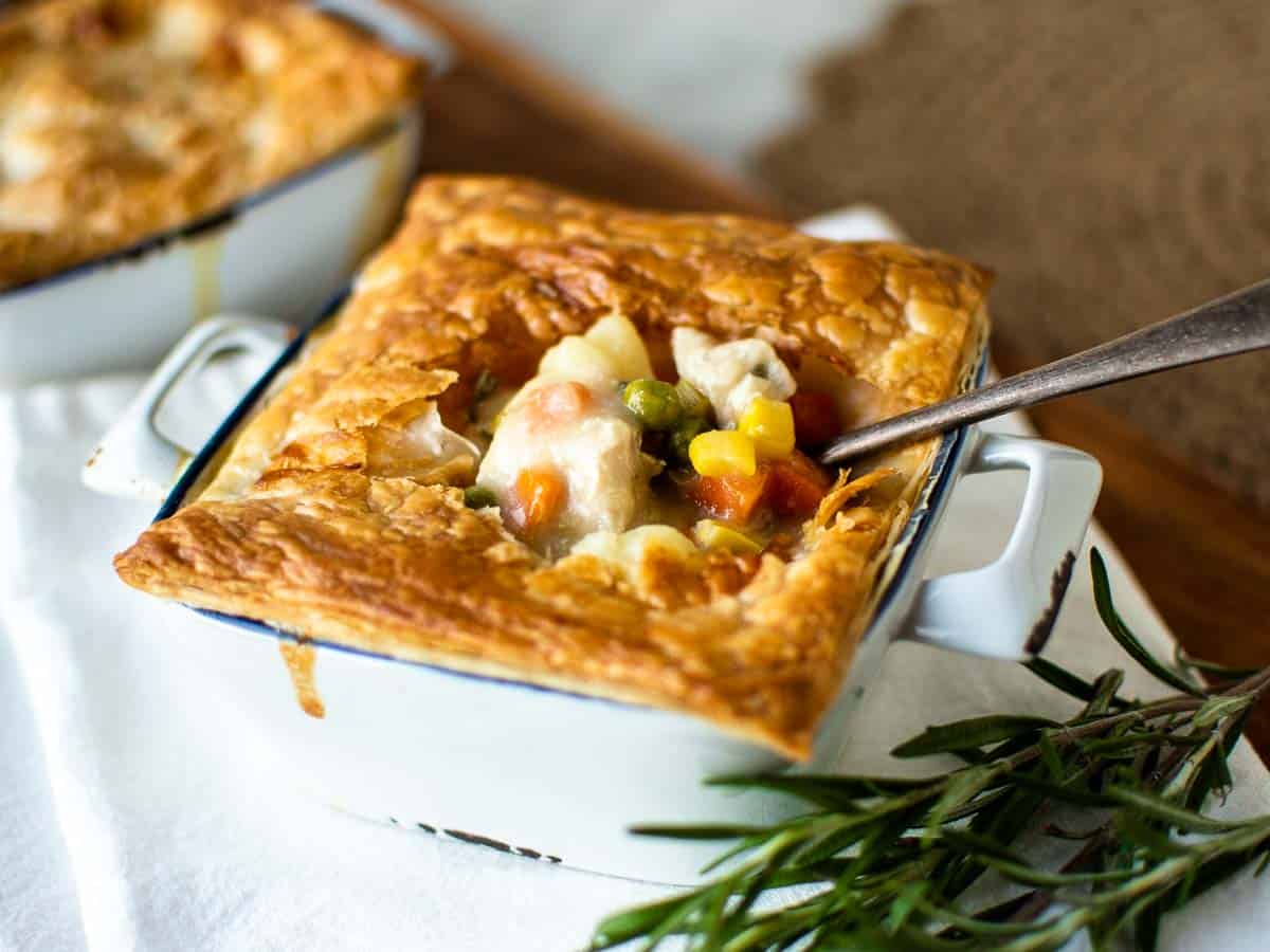 Individual chicken pie in a ramekin crust open to reveal filling.