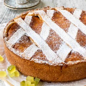 round high crusted pie with lattice top dusted with powdered sugar, espresso in the background.