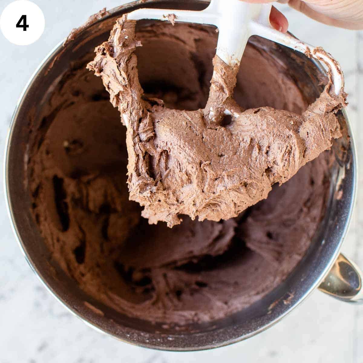 Chocolate frosting on the paddle of a stand mixer.