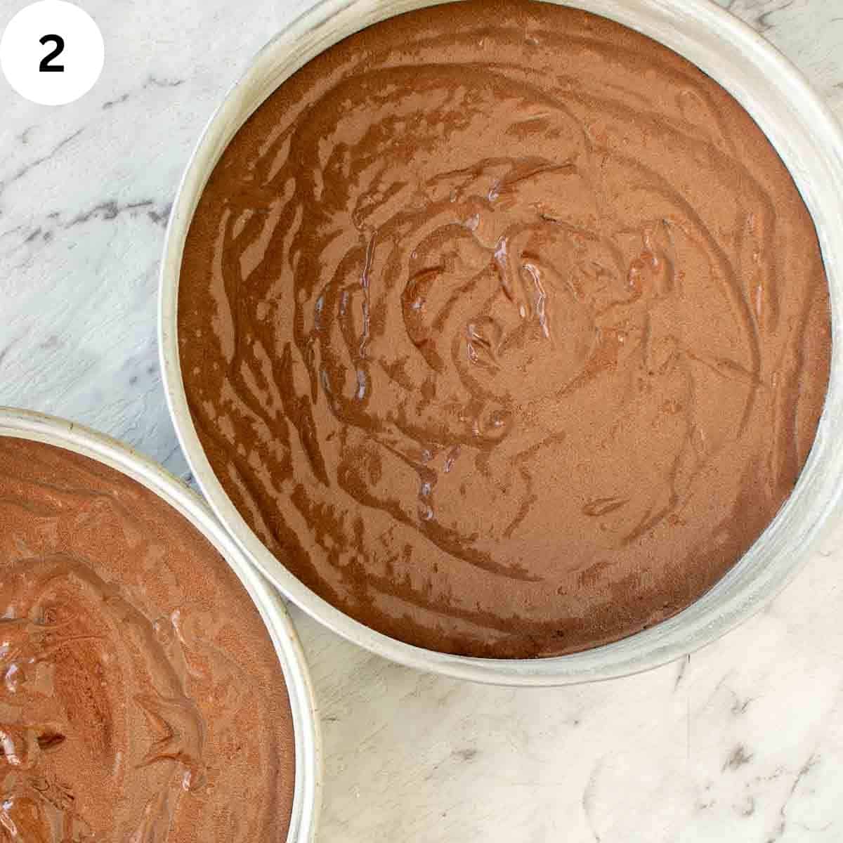 Chocolate cake batter in two round cake pans viewed from above.