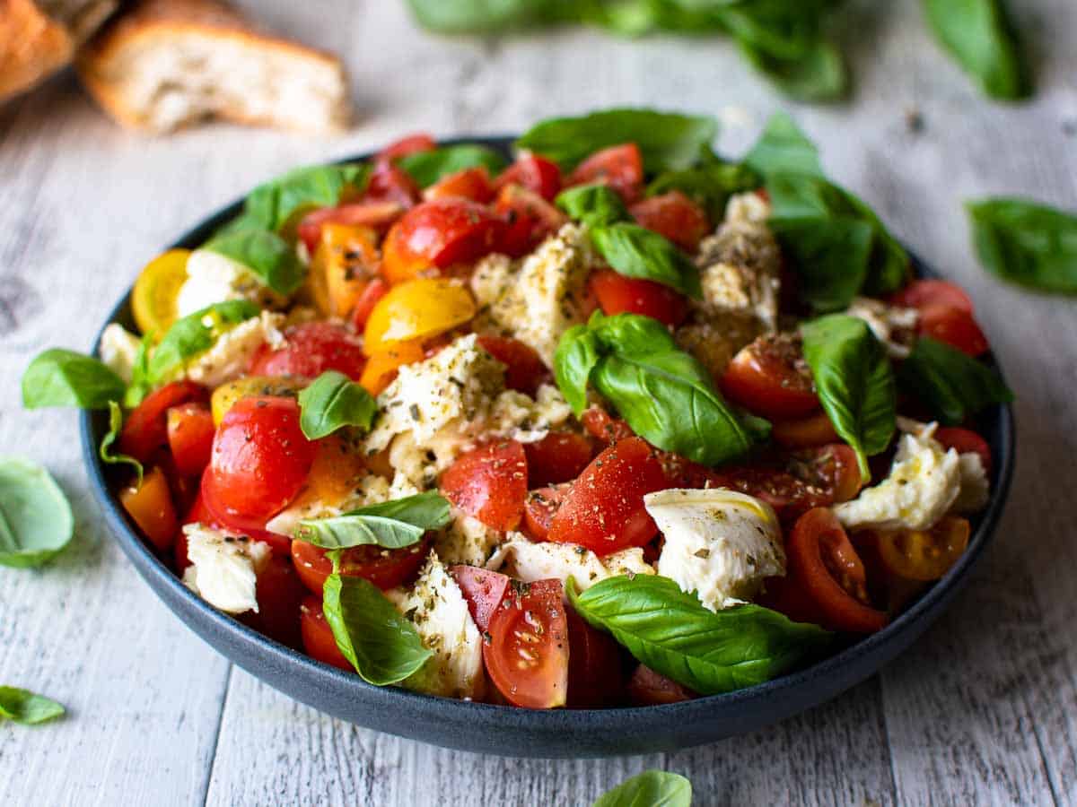 Close up of tomato, basil and mozzarella salad in a shallow bowl.