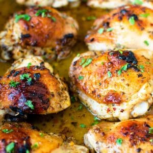 Baked Italian chicken thighs in baking pan garnished with parsley.