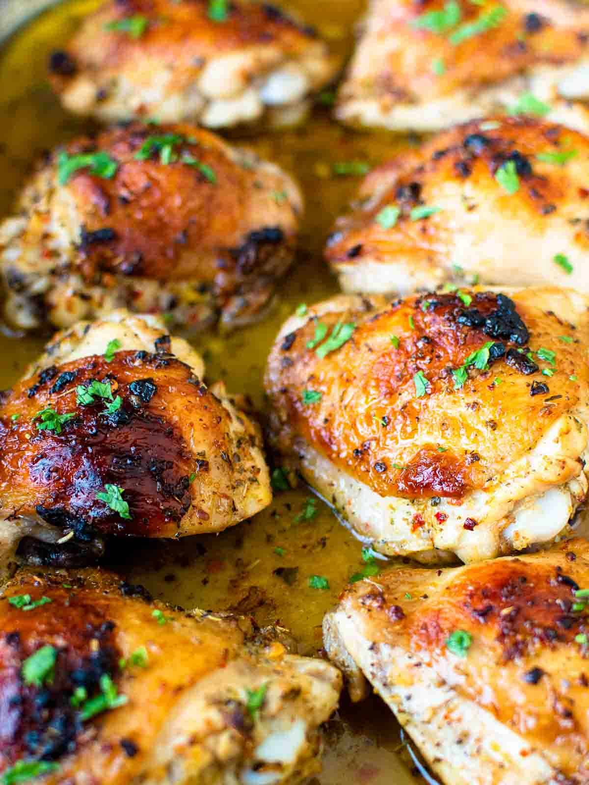 Baked Italian chicken thighs in baking pan garnished with parsley.