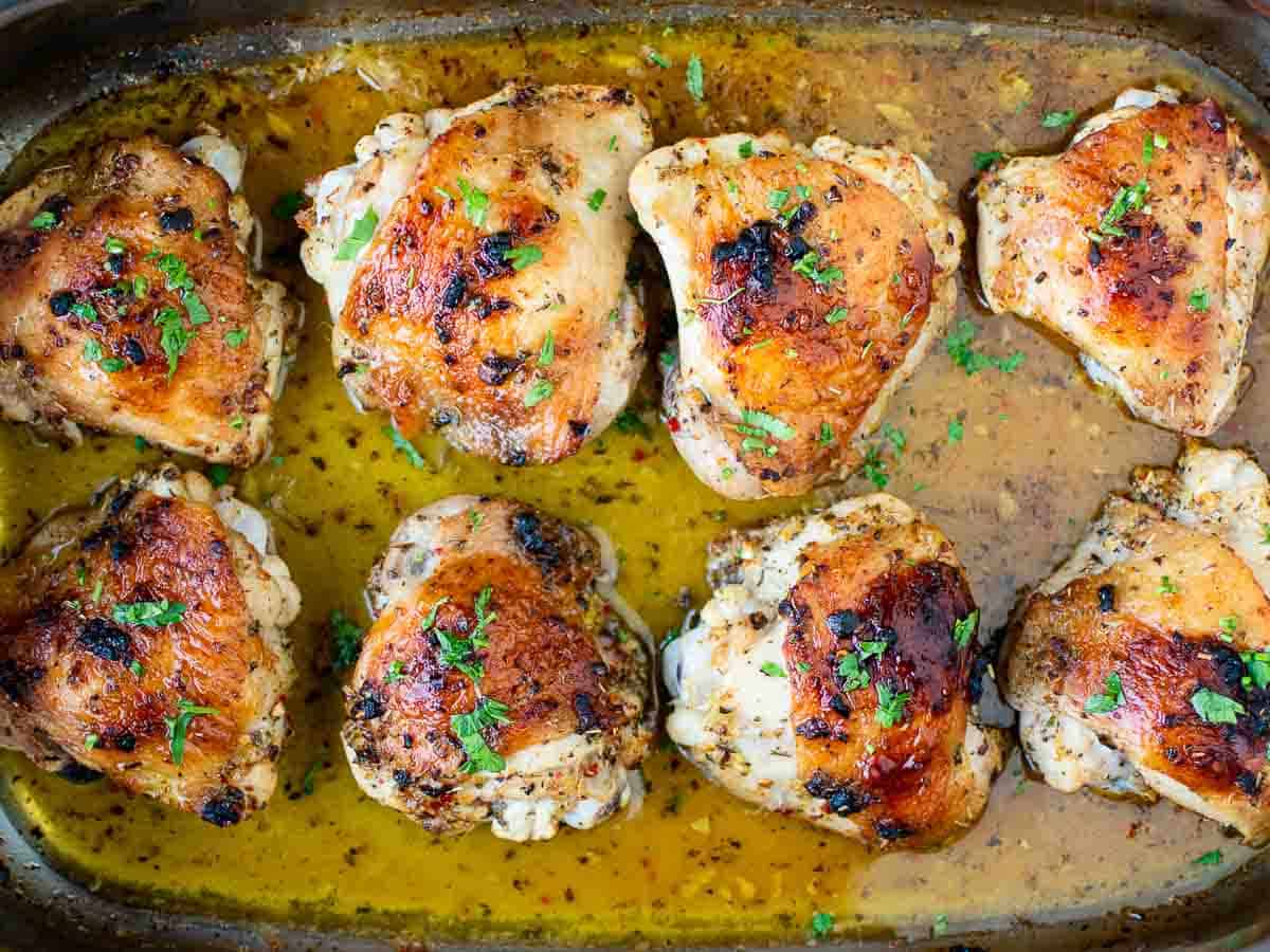 Overhead view of baked chicken thighs in baking pan.