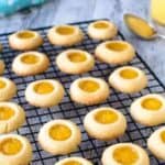 Rows of cookies with yellow centres on a black wire rack.