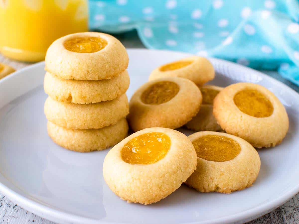 Stack of cookies with yellow centres and extra cookies on white plate.