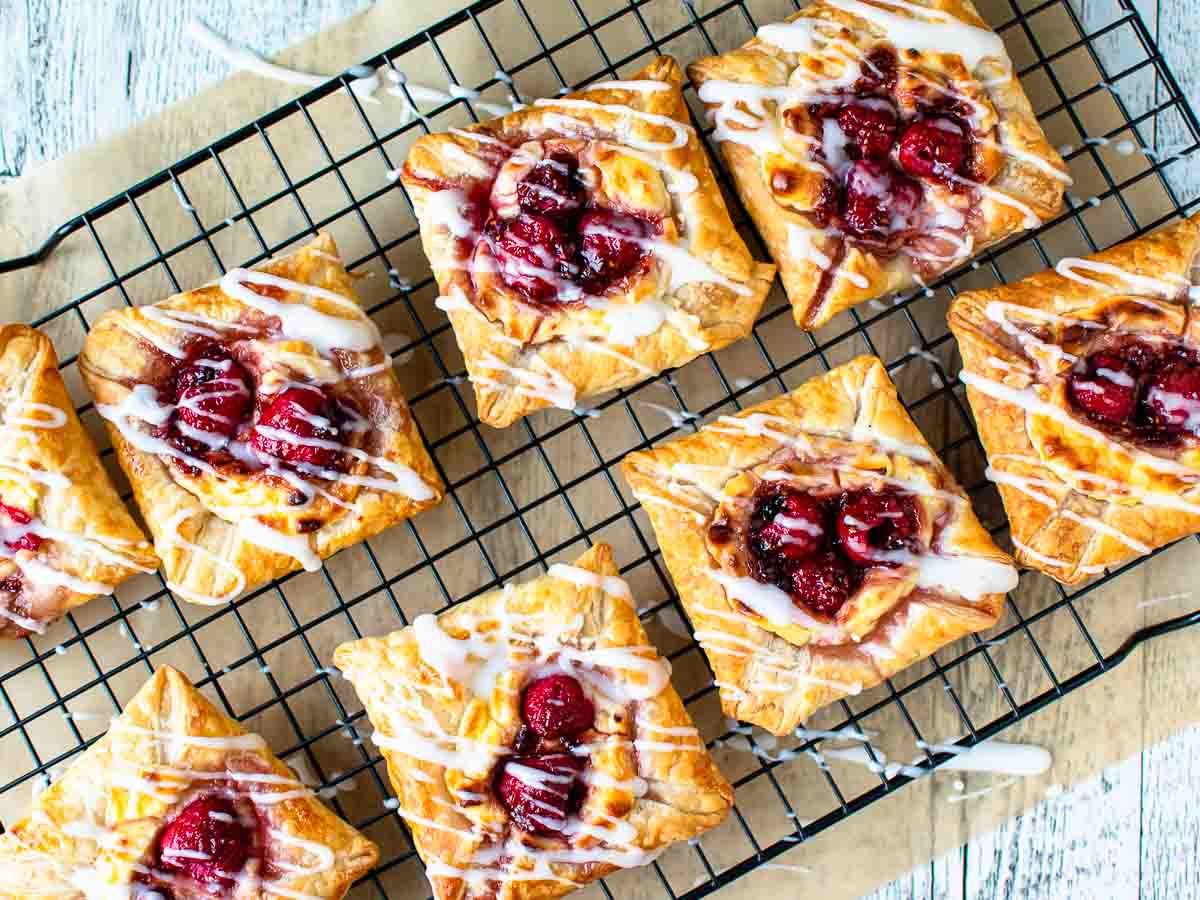 Raspberry pastries on black wire rack viewed from above.