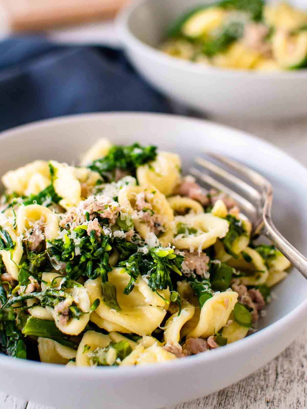 Sausage broccolini pasta in a grey bowl with a fork.