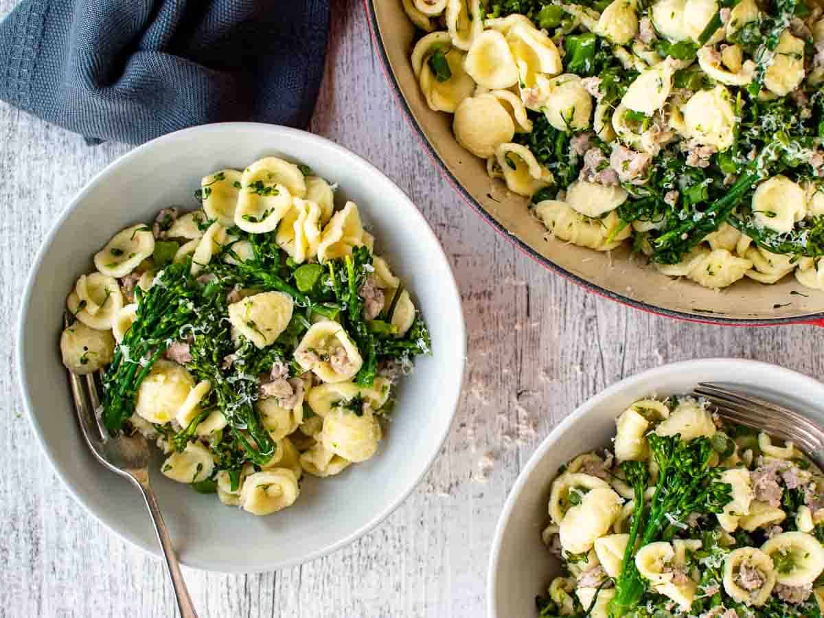 Overhead view of pasta and broccolini in two bowls and in pan.