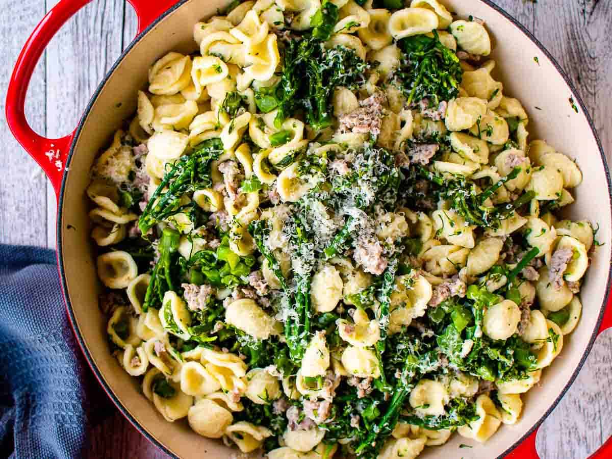 Pasta with broccoli and sausage in a saute pan viewed from above.