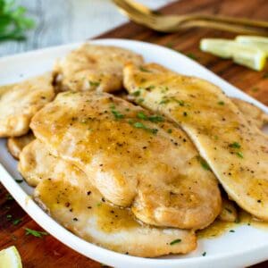 Chicken Limone on a white plate garnished with chopped parsley.