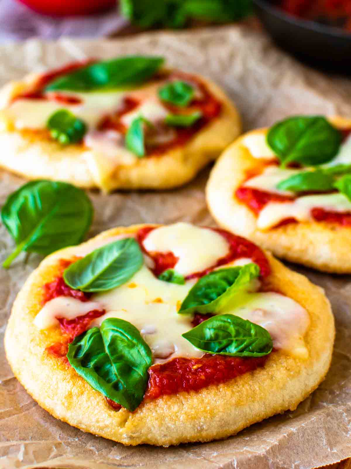 Three pizza fritta in a staggered row with tomato sauce, cheese and basil leaves.