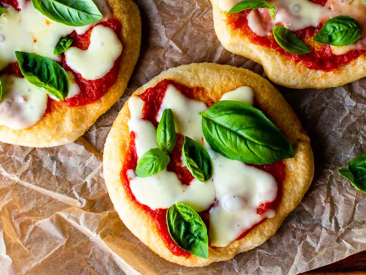 Overhead view of pizza with tomato sauce, cheese and basil leaves on top.
