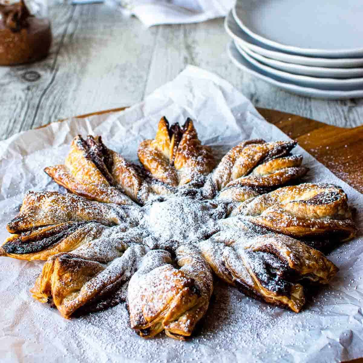 Star shaped pastry with dusting of powdered sugar on white paper.