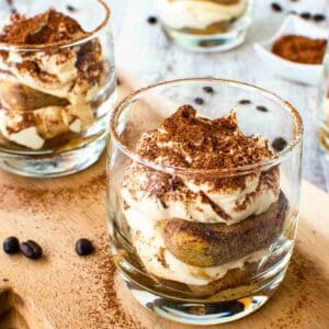 Tiramisu cups on wooden board.