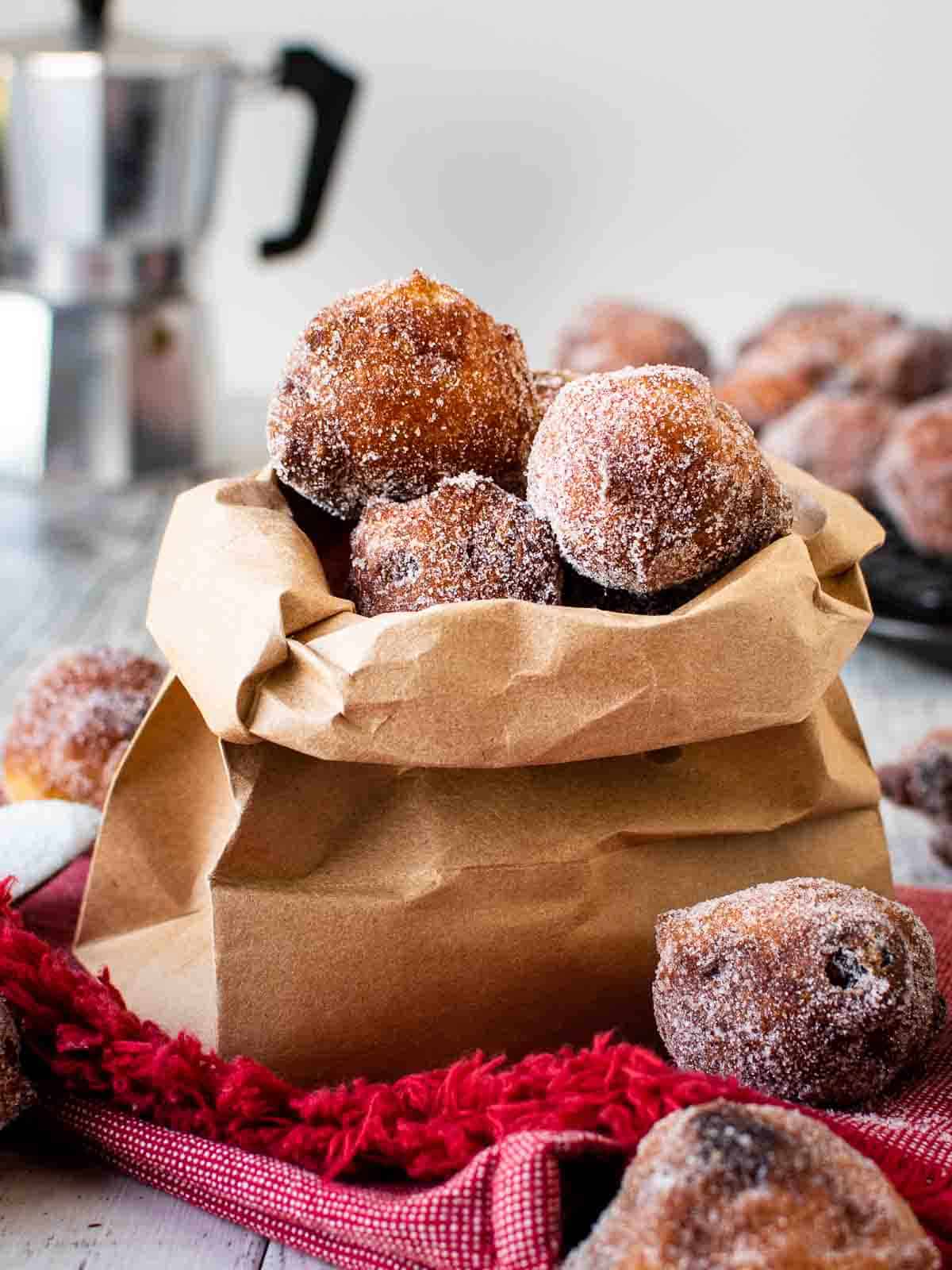 Frittelle coated in sugar in a brown paper bag.