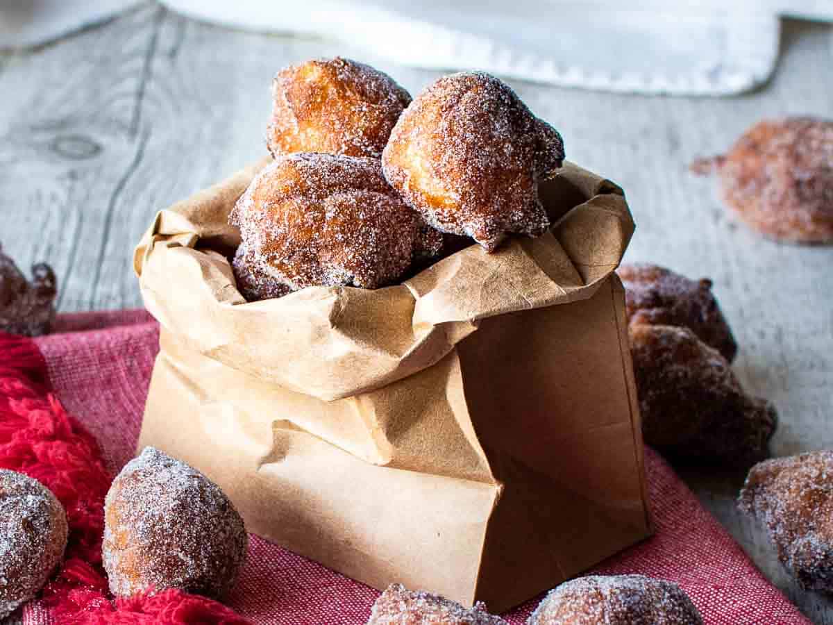 Fried dough balls piled into a paper bag with some spilling out.They are seriously festive and a quintessential Italian holiday treat.