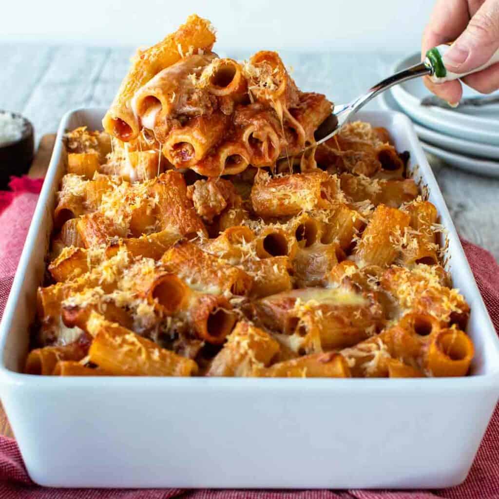 Pasta al forno in a white baking dish with a scoopful lifted up.