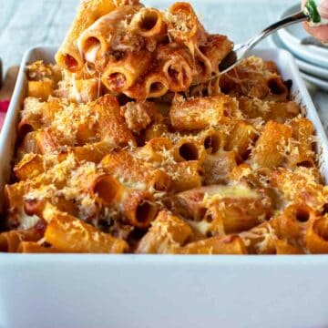 Pasta al forno in a white baking dish with a scoopful lifted up.