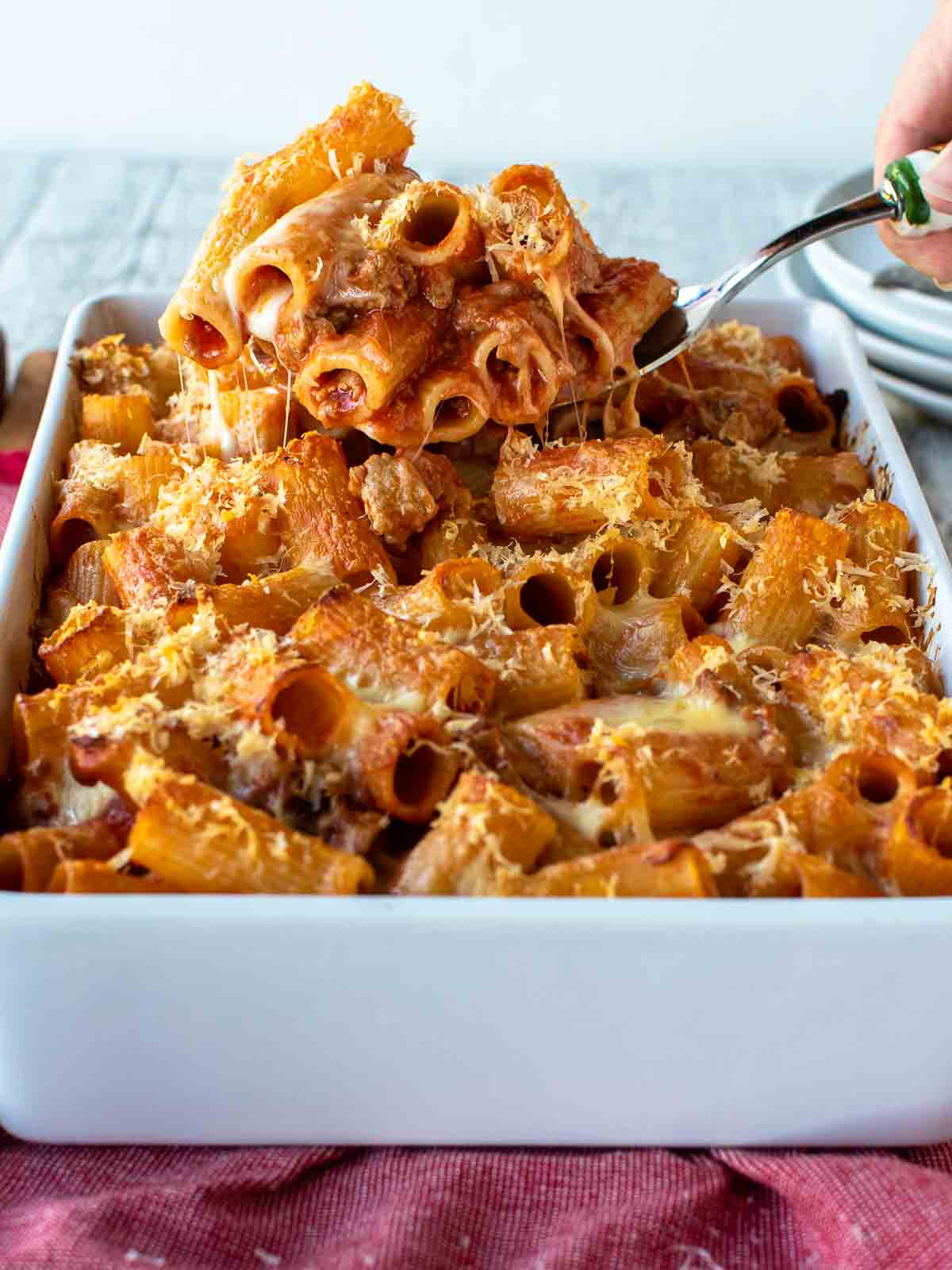 Pasta al forno in a white baking dish with a scoopful lifted up.